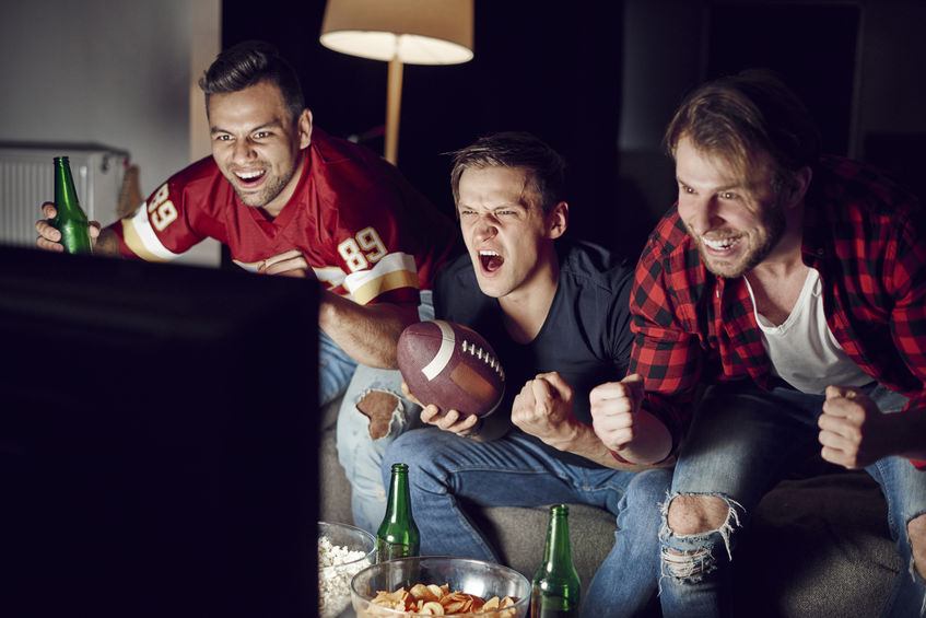 Men excitedly watching a sports game on TV