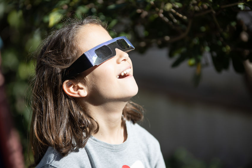 Surprised girl watching a solar eclipse of the sun with eclipse glasses