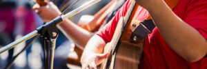 Selective focus to musician's hands playing guitar at a live show on stage, the concept of musical instrument.