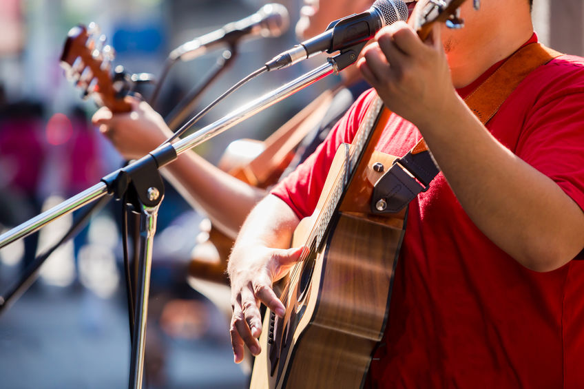 Selective focus to musician's hands playing guitar at a live show on stage, the concept of musical instrument.